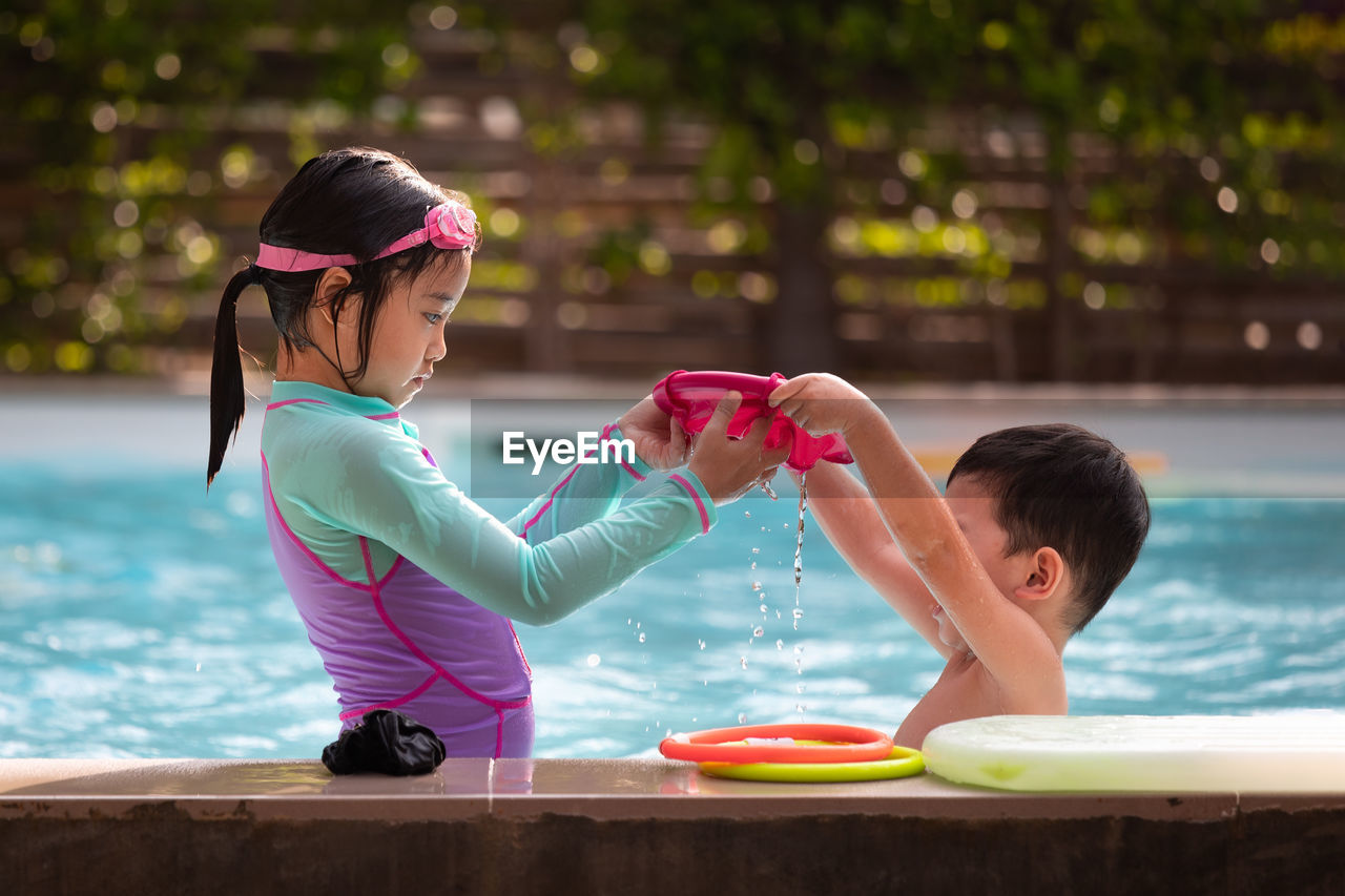 Siblings enjoying at swimming pool