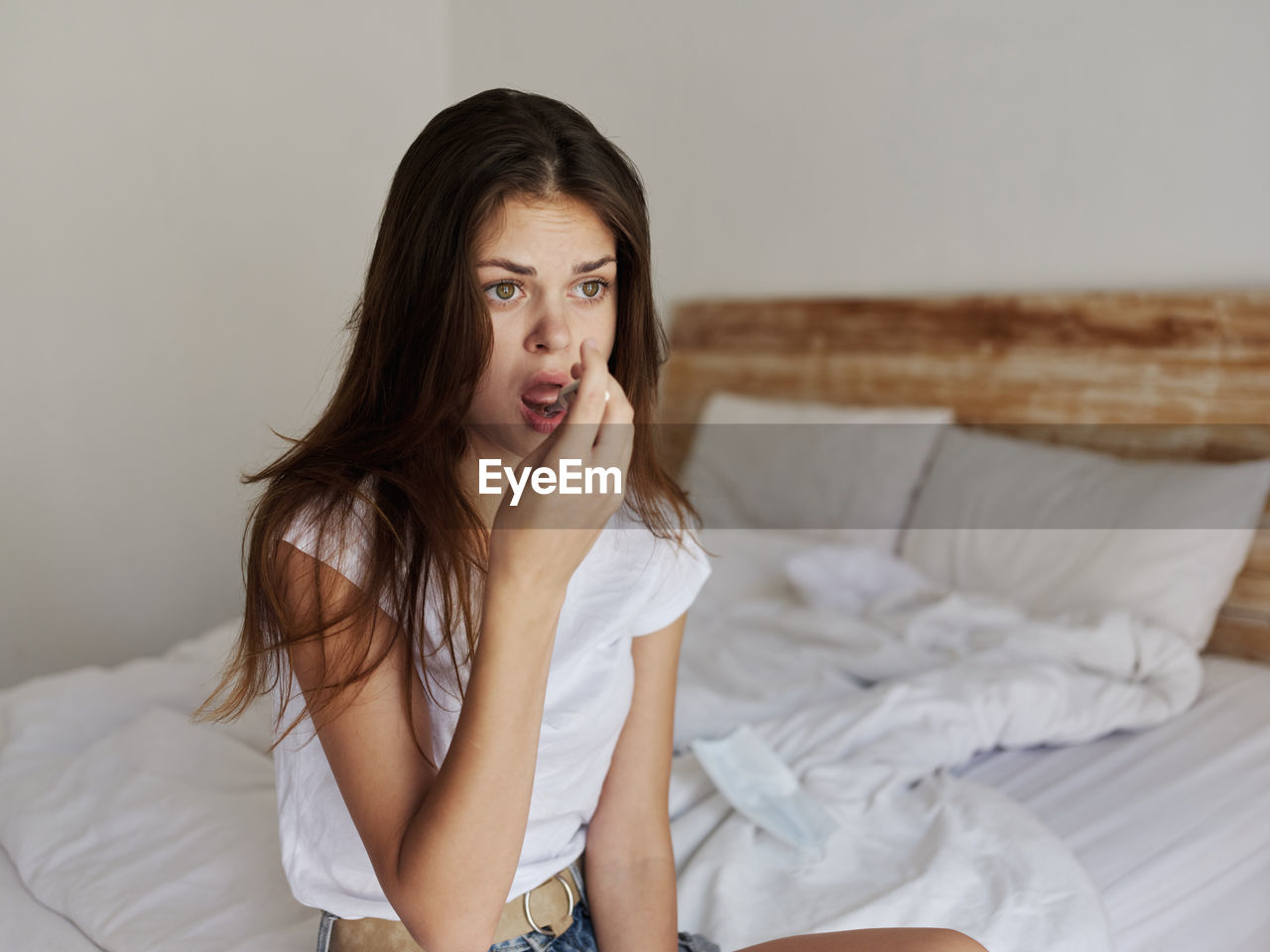 Portrait of young woman sitting on bed at home