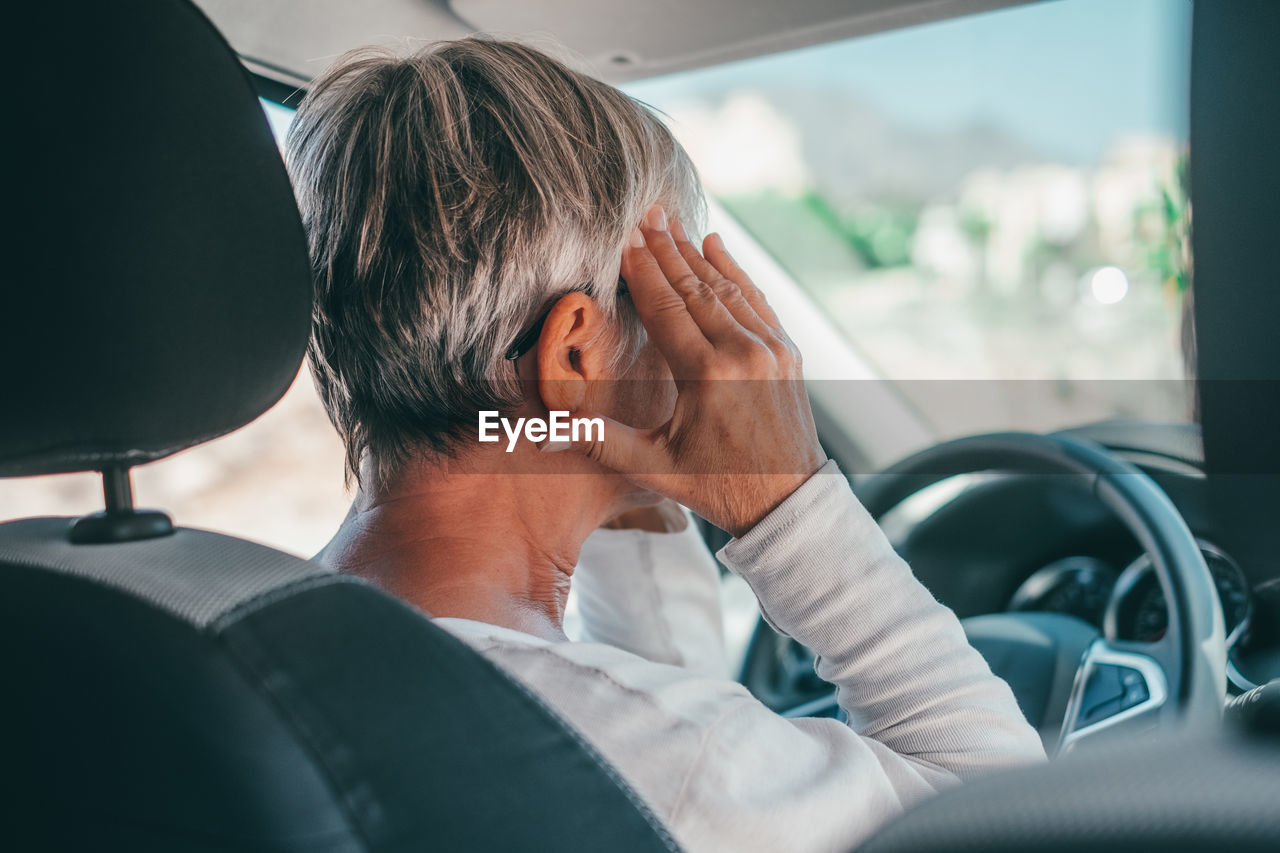 Senior woman having headache in car