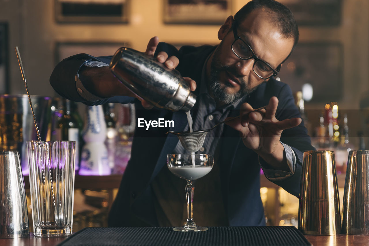 Male bartender preparing cocktail at bar counter