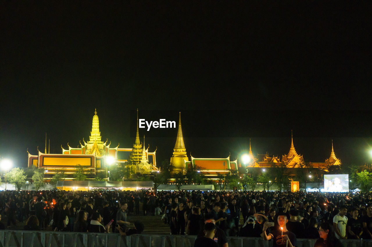 Crowd at illuminated temple against sky at night