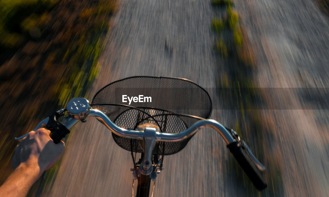 Close-up cropped hand riding bicycle on road