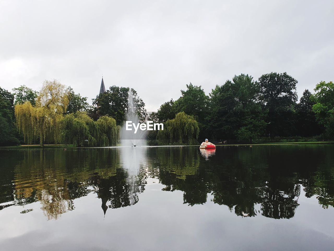 REFLECTION OF TREES IN LAKE AGAINST SKY