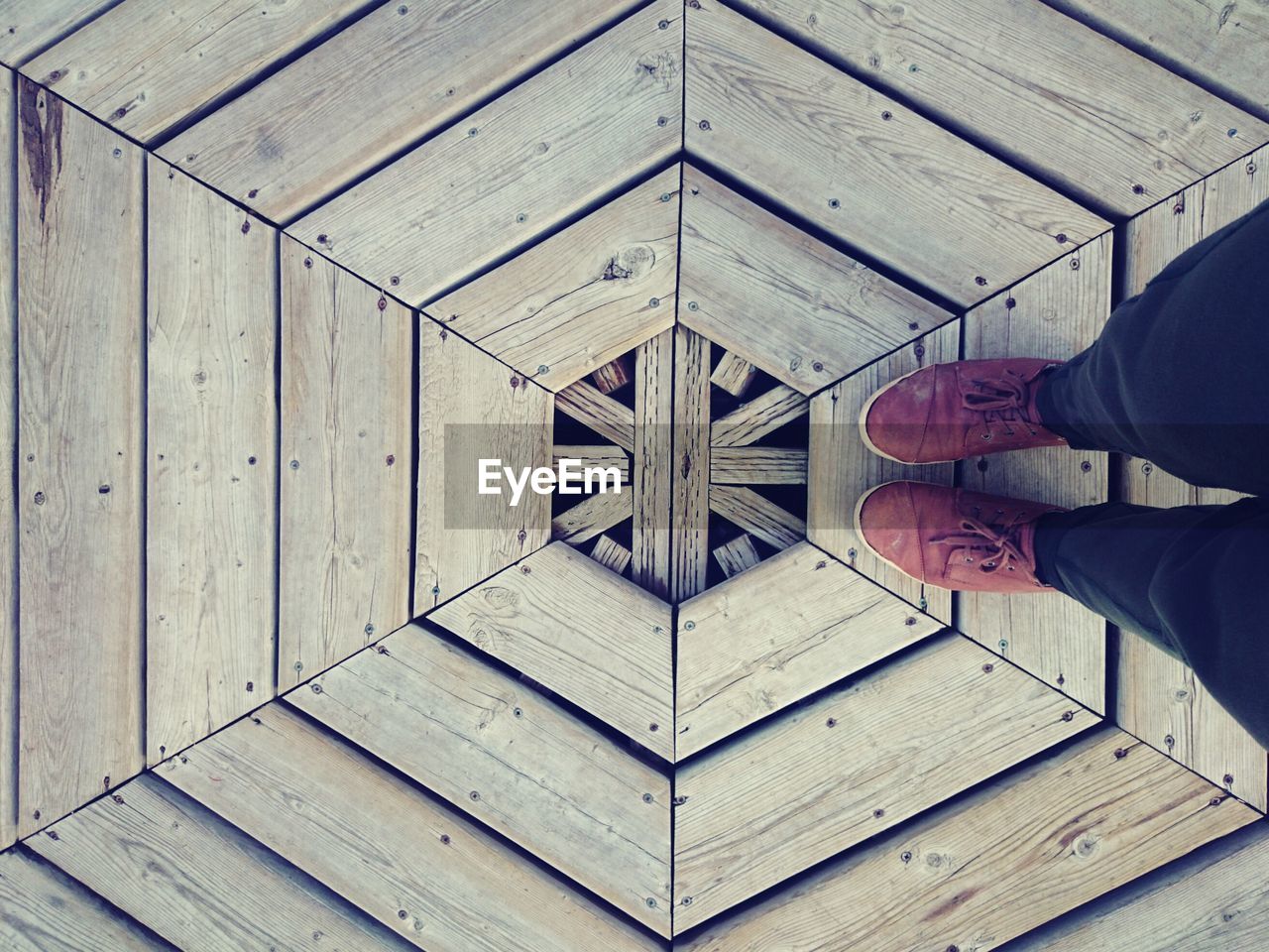Low section of person standing on hexagon shape wooden floor
