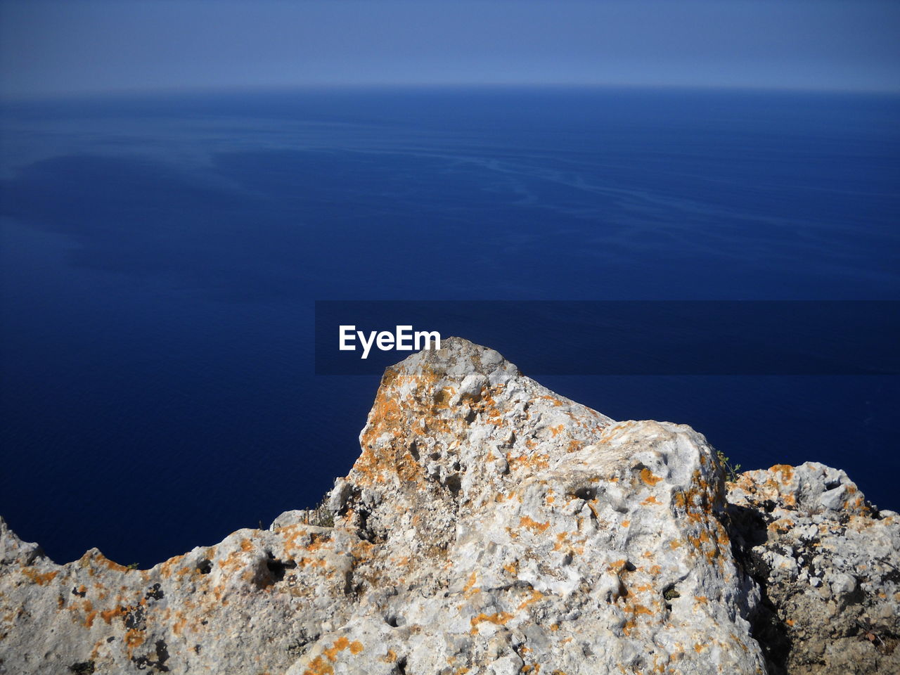 Rock formations by sea against blue sky