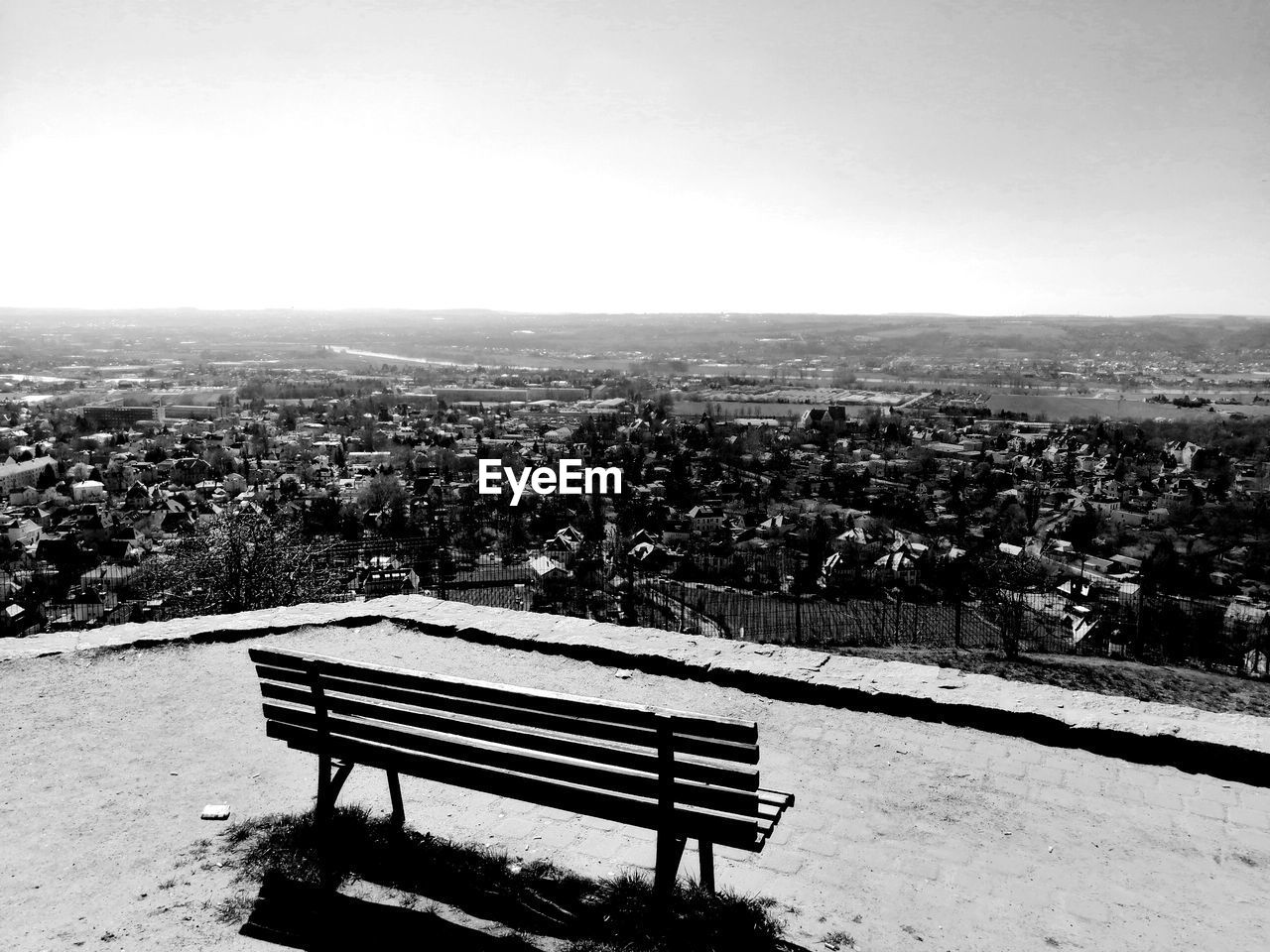 HIGH ANGLE VIEW OF PARK BENCH BY BUILDING AGAINST SKY