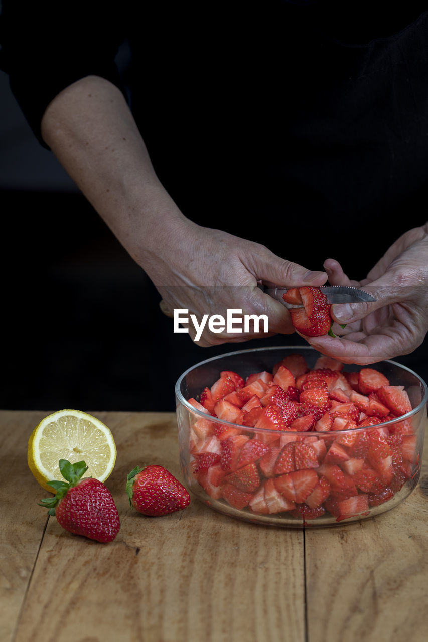 Female hands cutting strawberries. vertical.