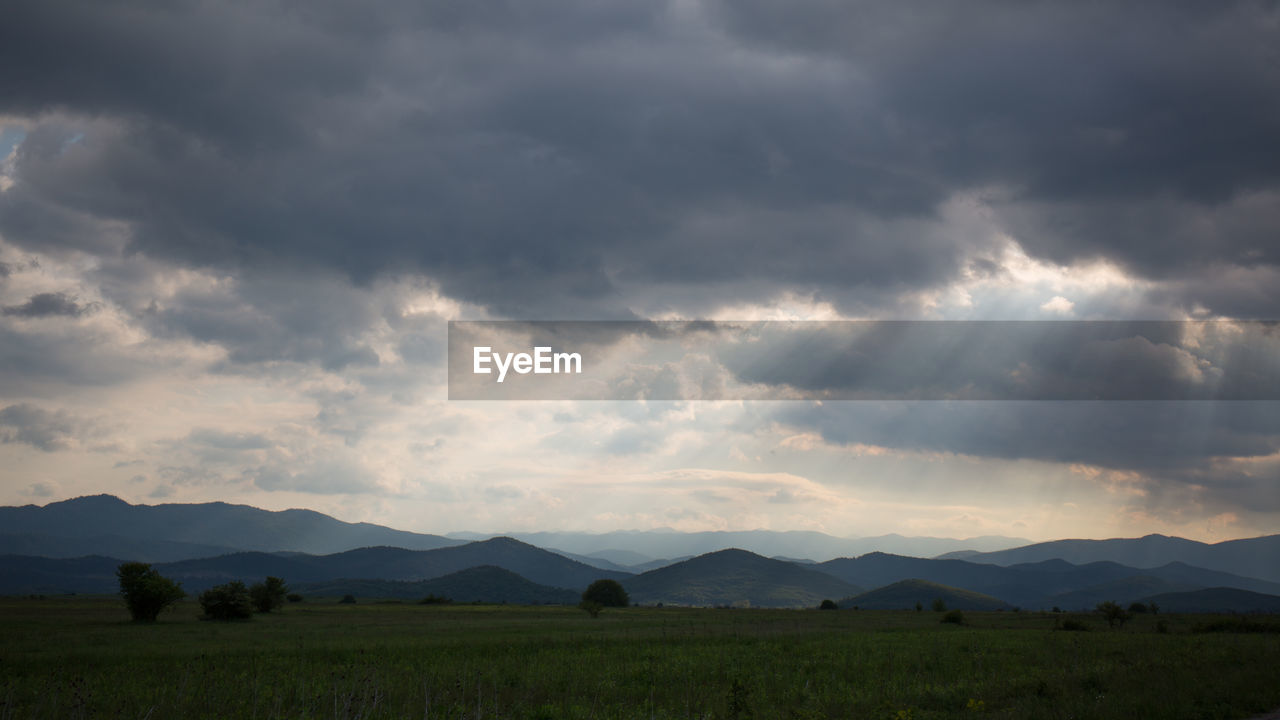 Scenic view of landscape against storm clouds