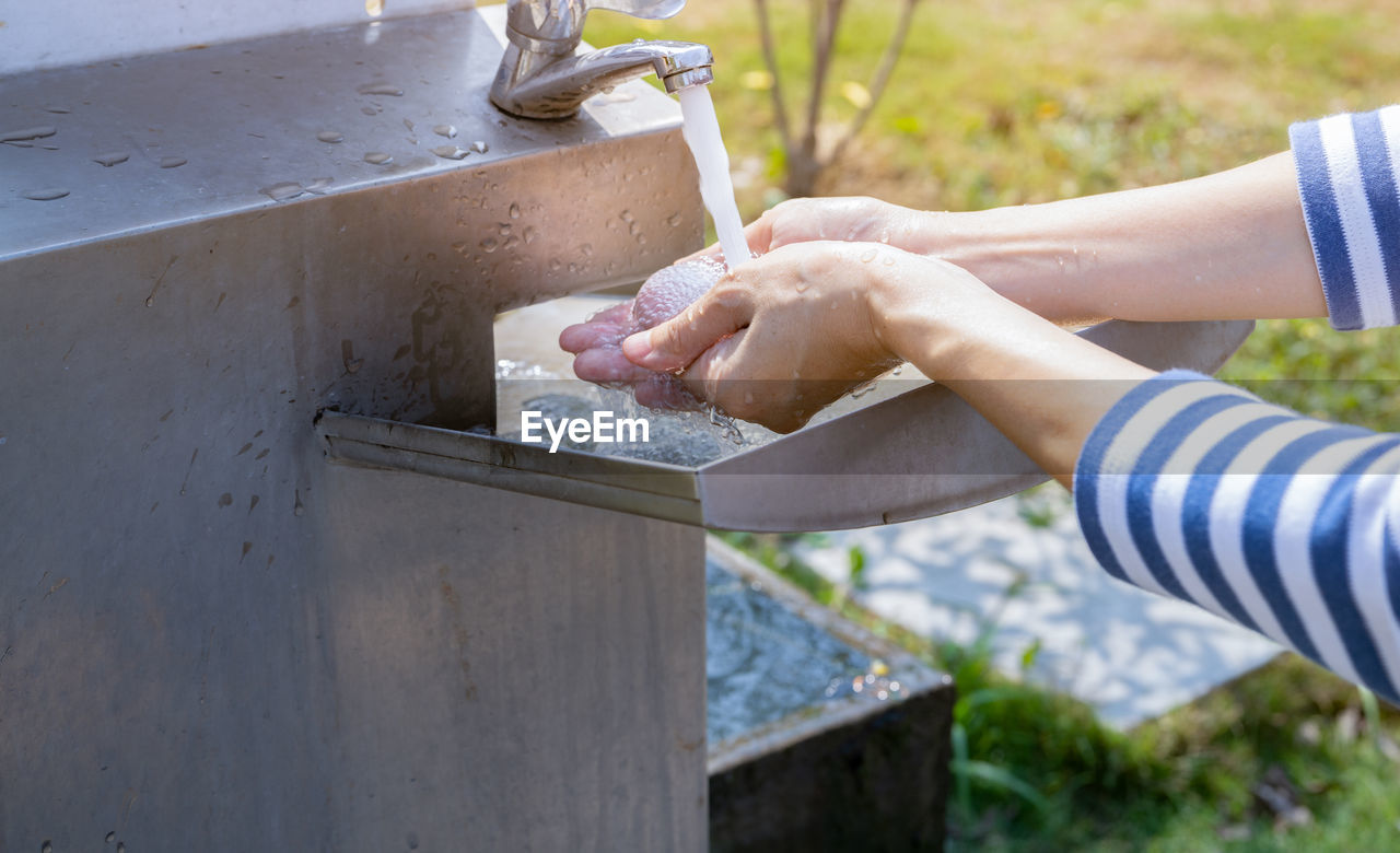 World water day concept. woman washing hands with tap water under faucet at stainless steel sink. 