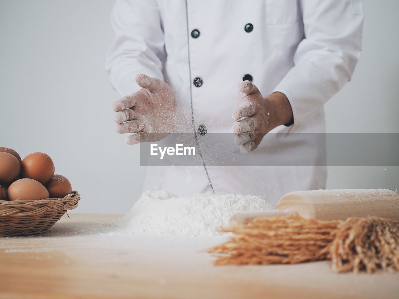 Midsection of chef preparing food on table against white background