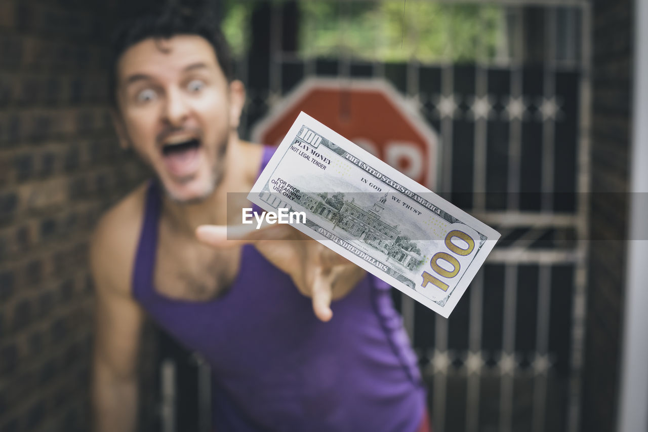 Portrait of man reaching for his money floating in the wind, while standing outdoors.