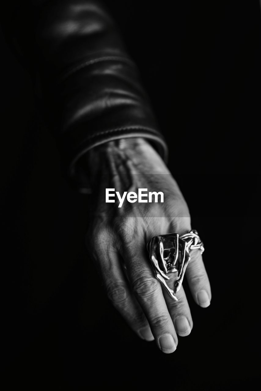 Cropped hand of woman wearing ring over black background