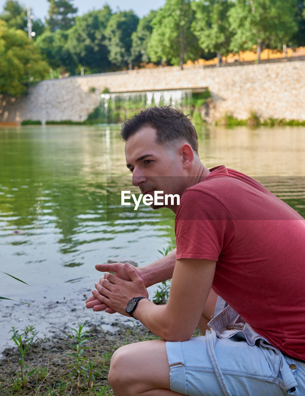 Side view of young man looking at lake