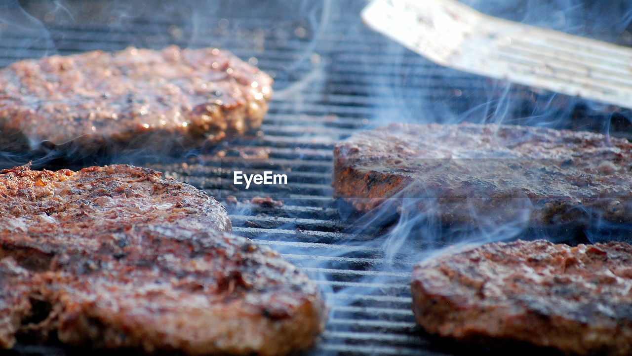 Hamburgers on an open grill outdoors.