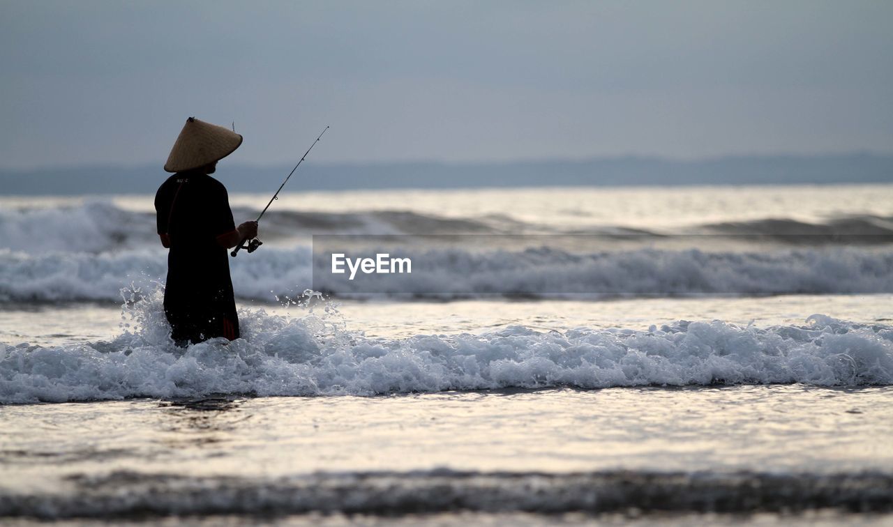 Rear view of fisherman at beach