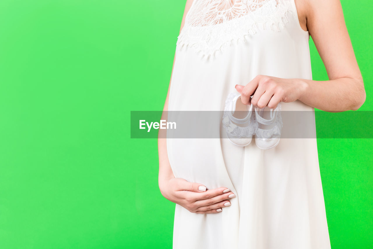 LOW SECTION OF WOMAN HOLDING WHITE DRESS