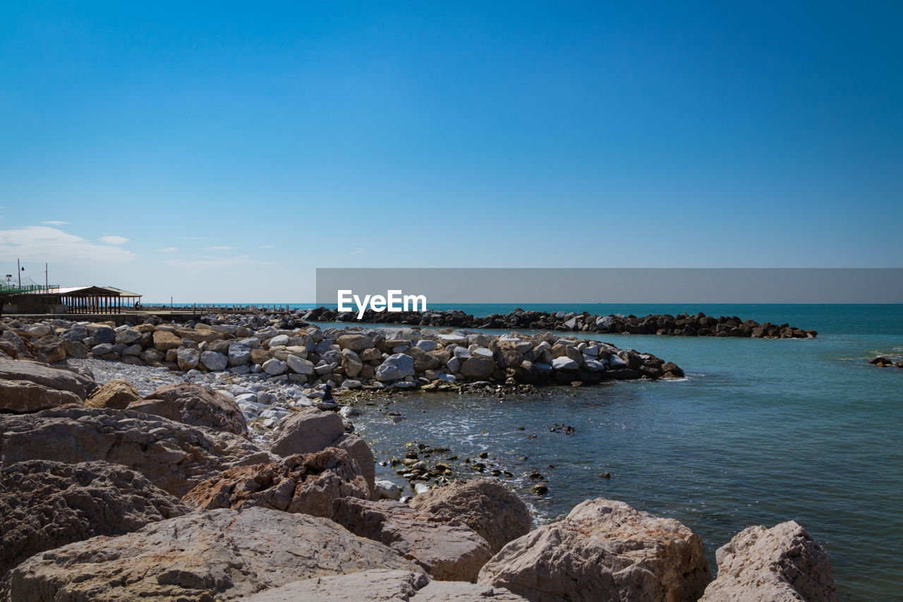 ROCKS BY SEA AGAINST SKY