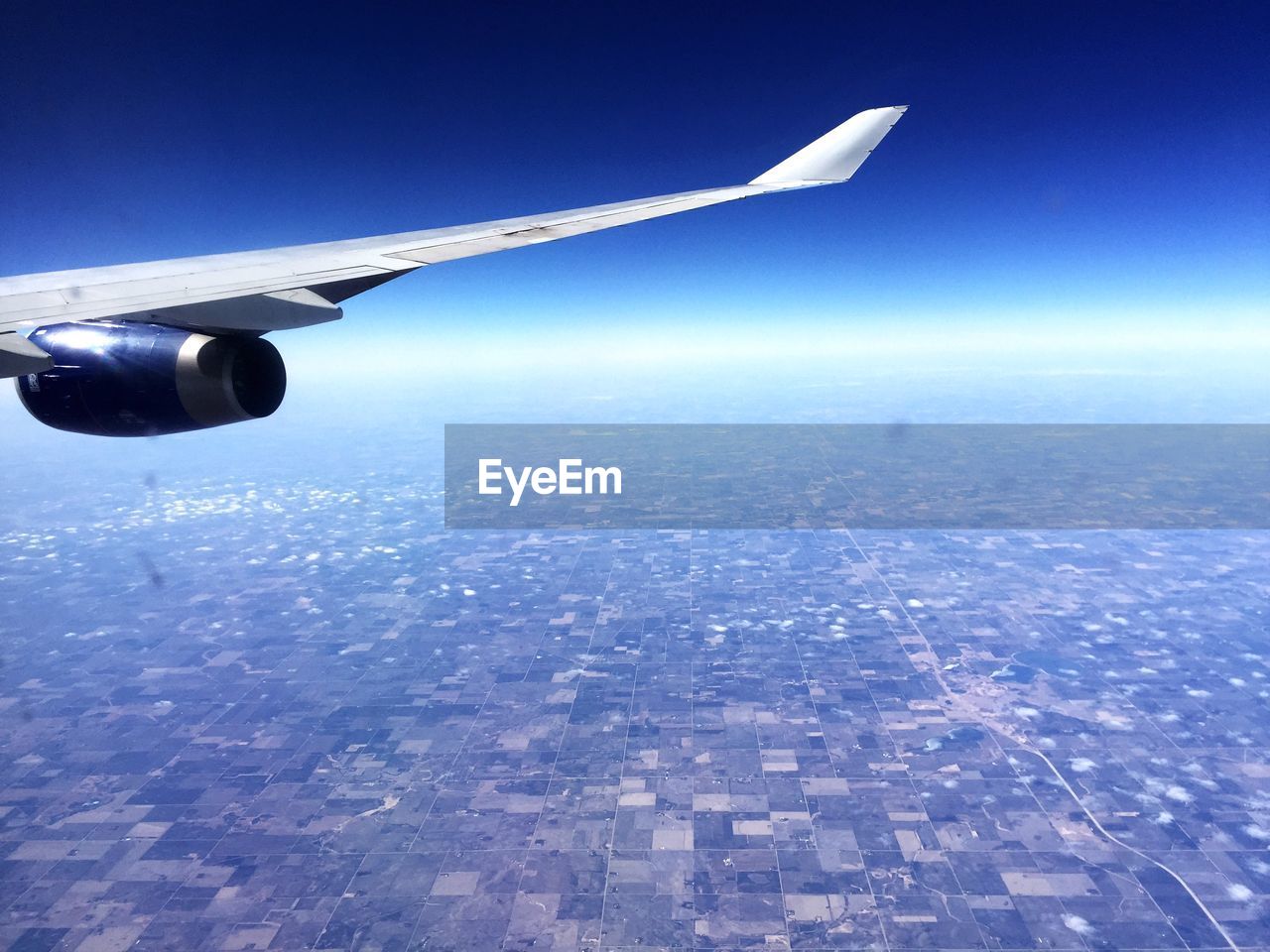 CROPPED IMAGE OF AIRPLANE WING OVER LANDSCAPE