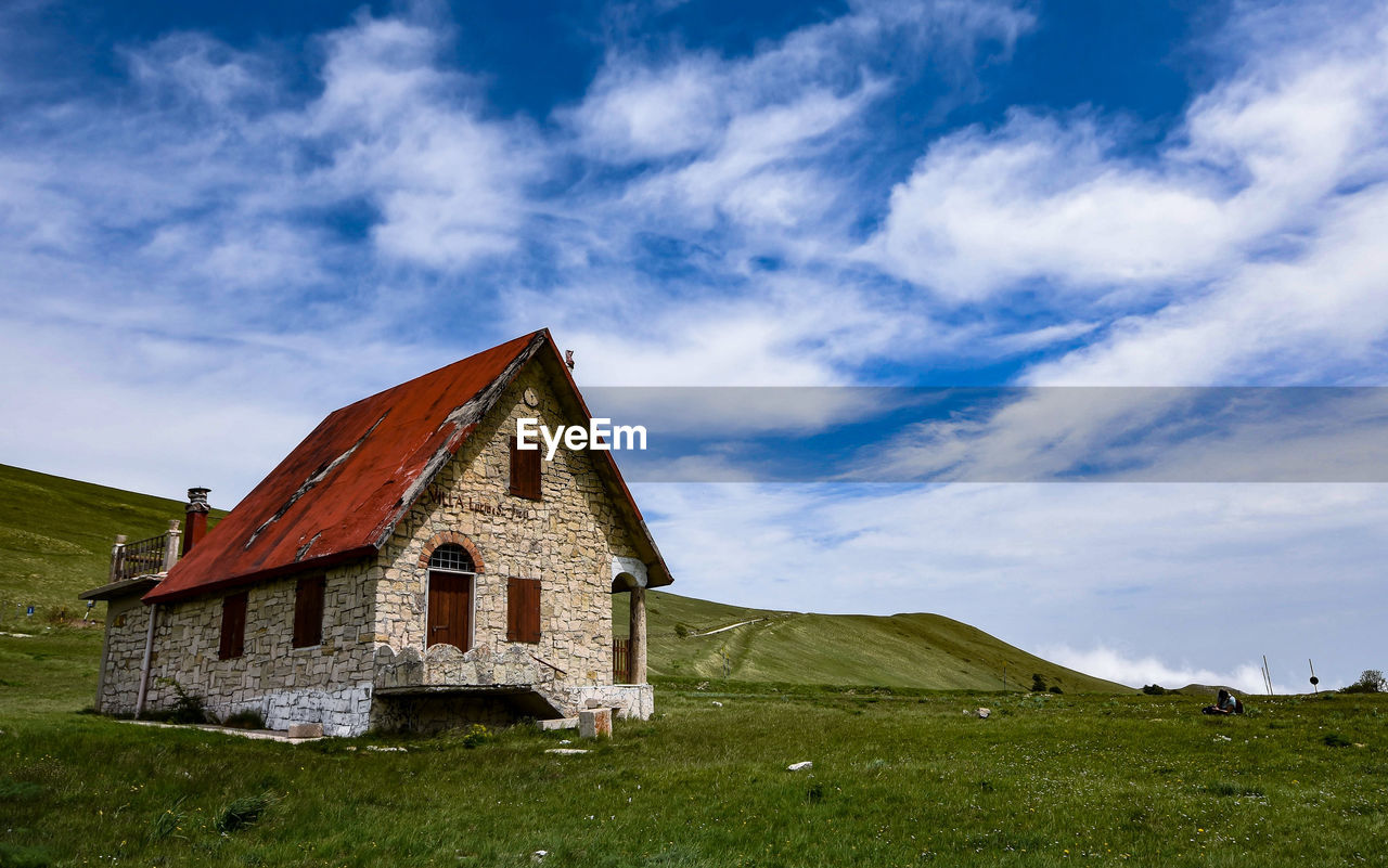 HOUSES ON FIELD AGAINST SKY