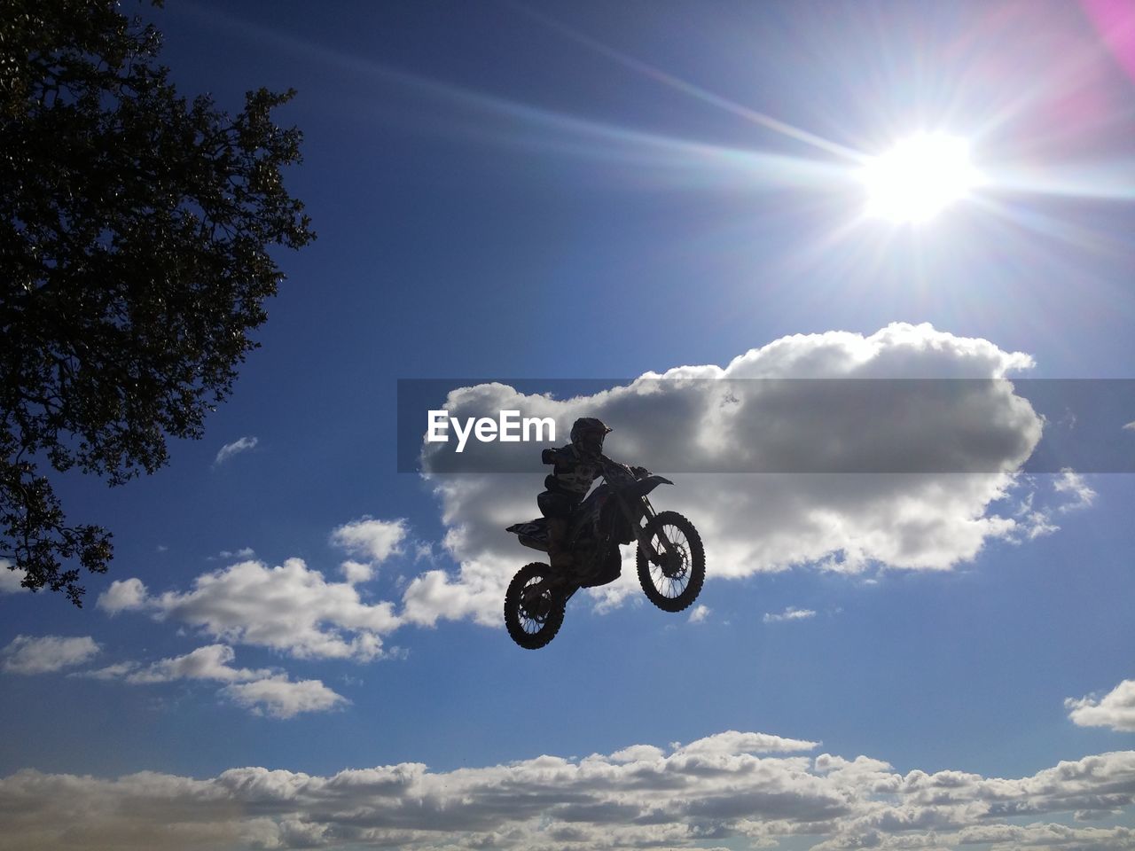 Low angle view of motocross racer performing mid-air stunt against sky