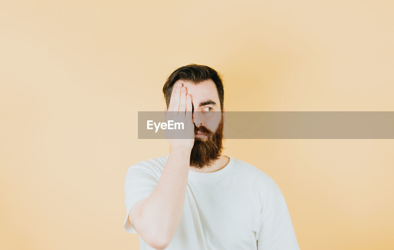 one person, studio shot, adult, portrait, indoors, young adult, copy space, colored background, waist up, facial hair, beard, front view, men, brown hair, headshot, casual clothing, human face, clothing, looking, white, photo shoot, looking at camera, standing, emotion, person, contemplation, hairstyle, lifestyles