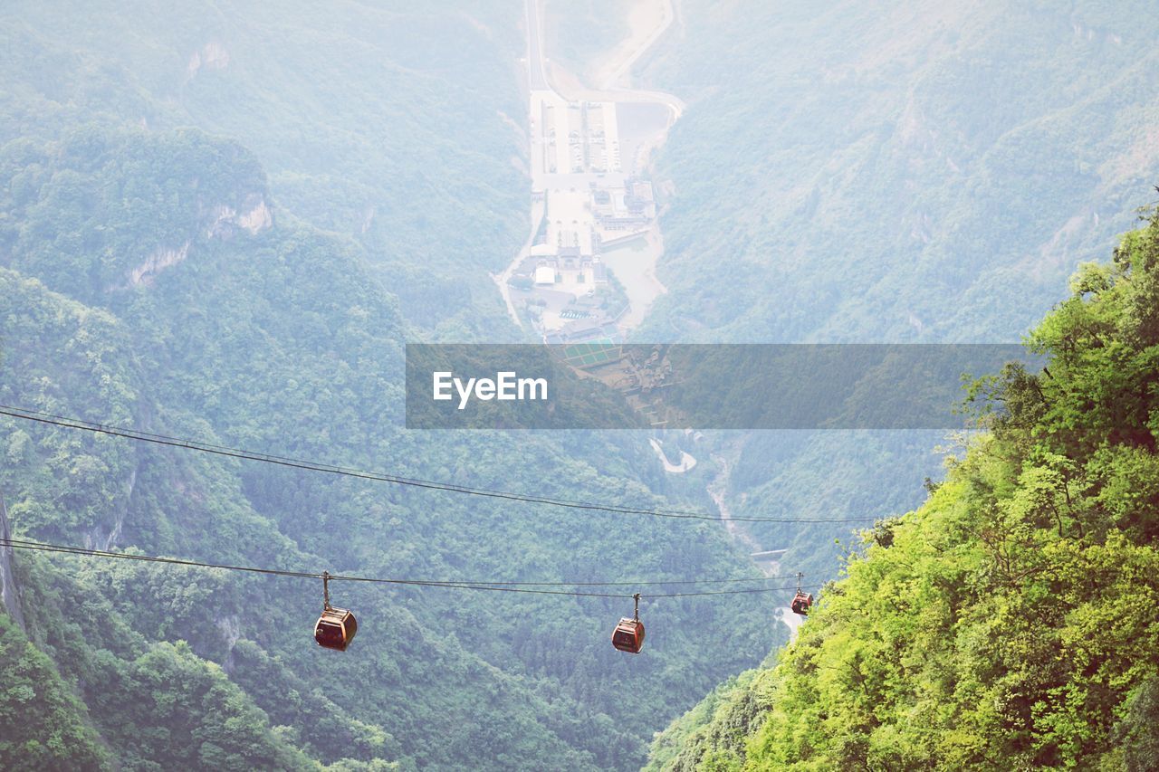 High angle view of overhead cable car by tree mountain