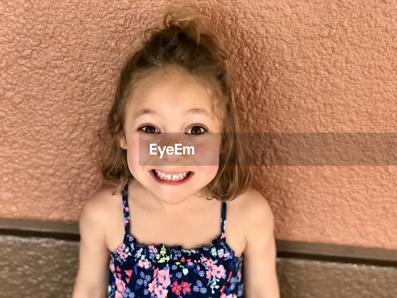 Portrait of smiling cute girl against wall