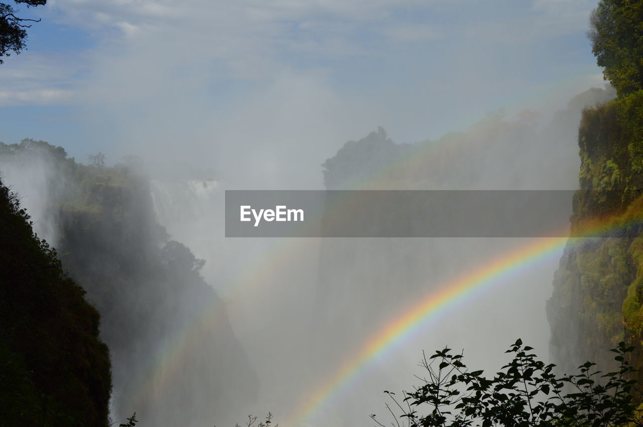 RAINBOW OVER MOUNTAIN AGAINST SKY