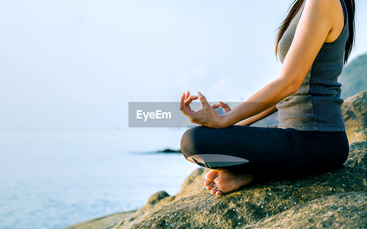 Young woman in lotus position on shore