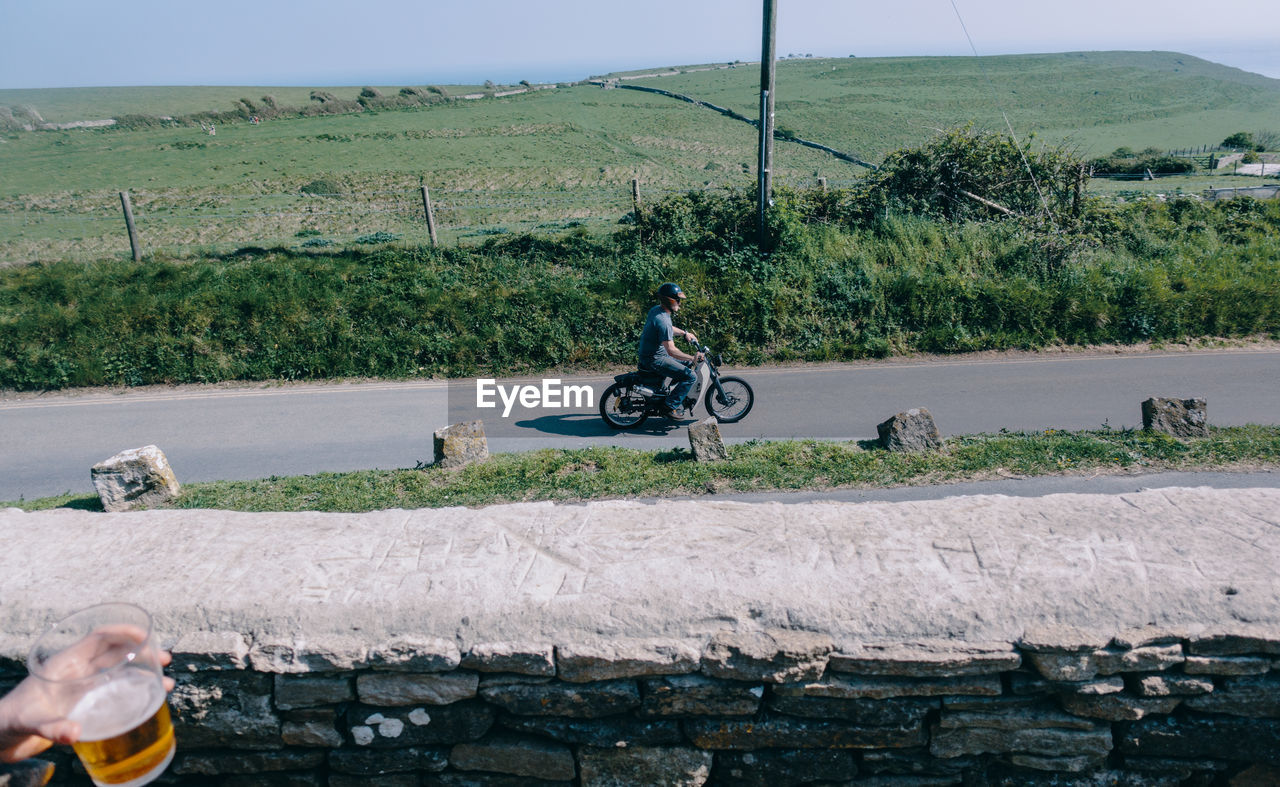 MAN RIDING BICYCLE BY ROAD