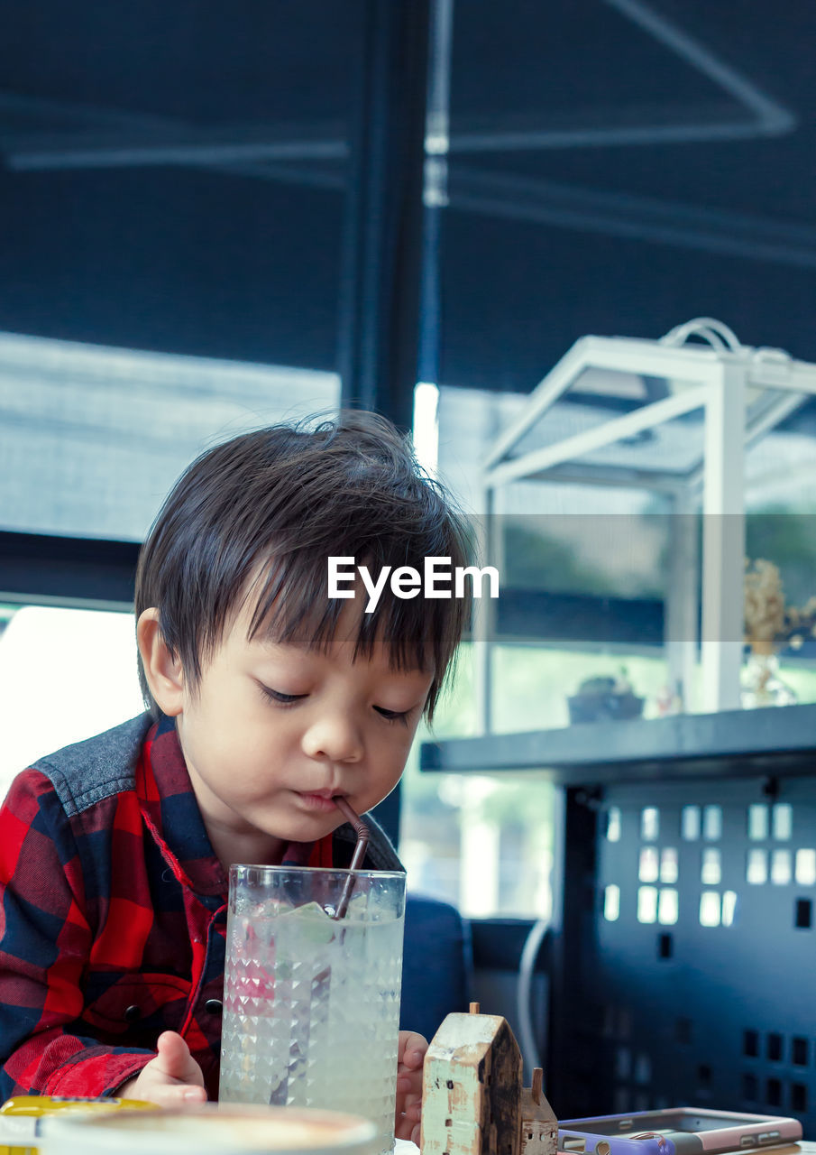 Cute boy drinking juice on table in restaurant