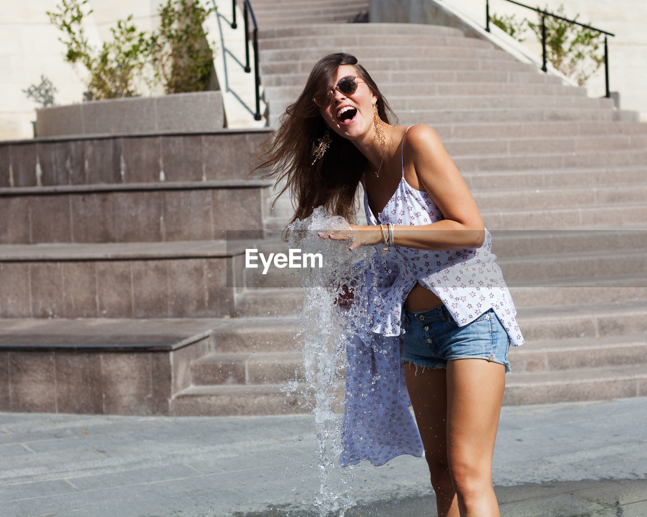 Happy woman playing with water by fountain