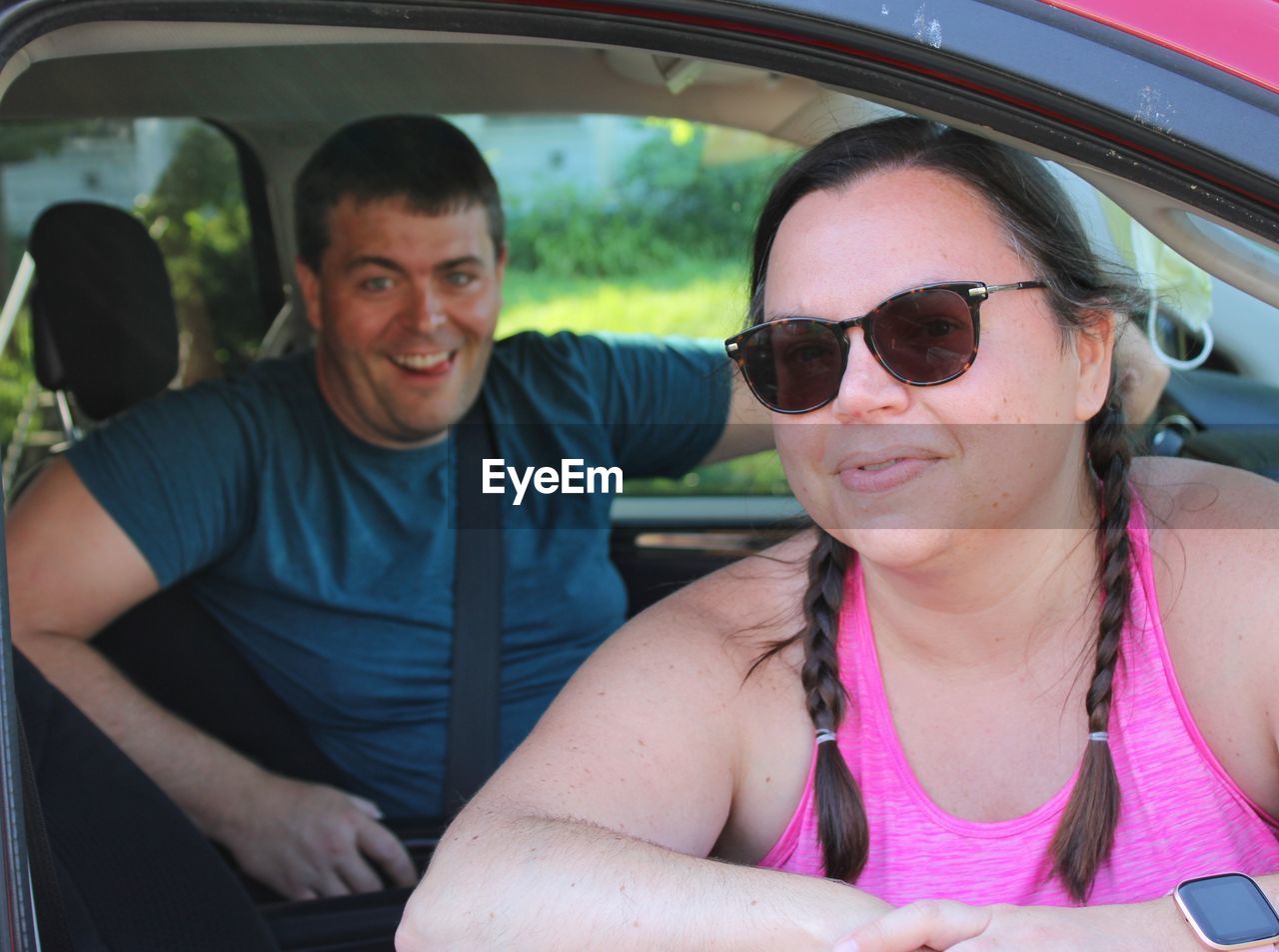 Portrait of cheerful couple sitting in car