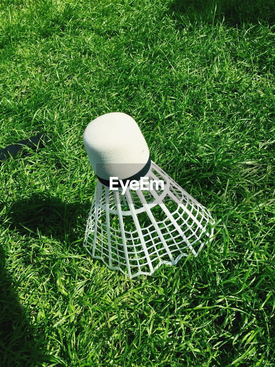 Close-up of shuttlecock on grassy field during sunny day