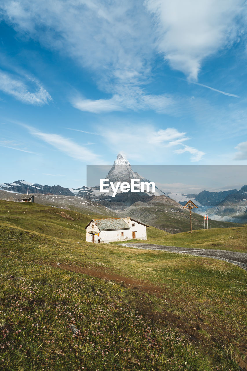 View of house on field against blue sky with matterhorn in the background
