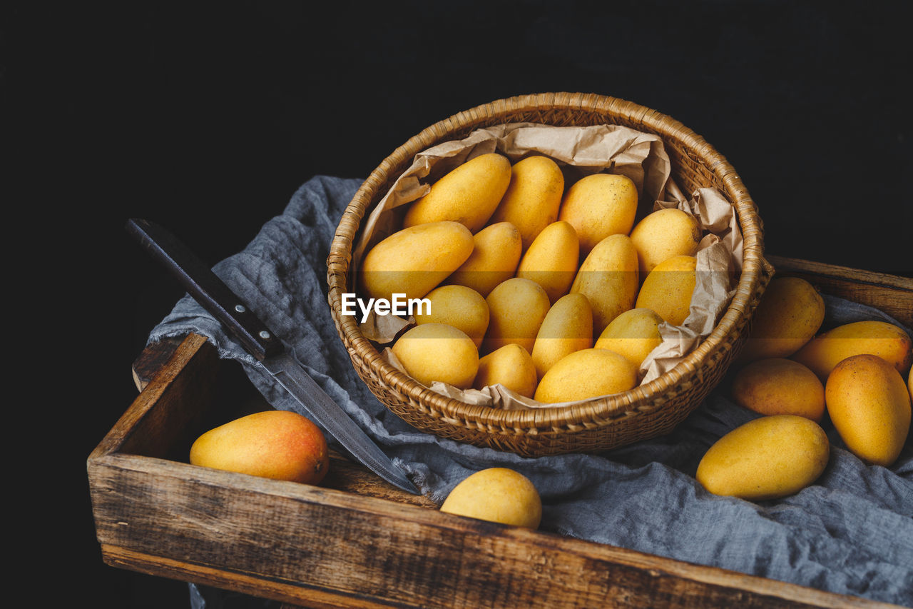 High angle view of mangoes in basket on wooden crate