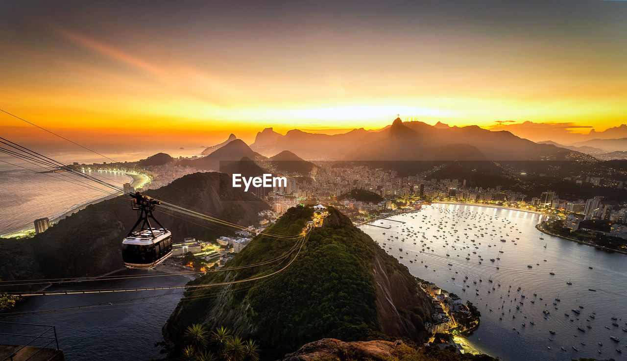 Breathtaking scenery of modern cable car riding above ocean and mountains against amazing sunset sky in rio de janeiro