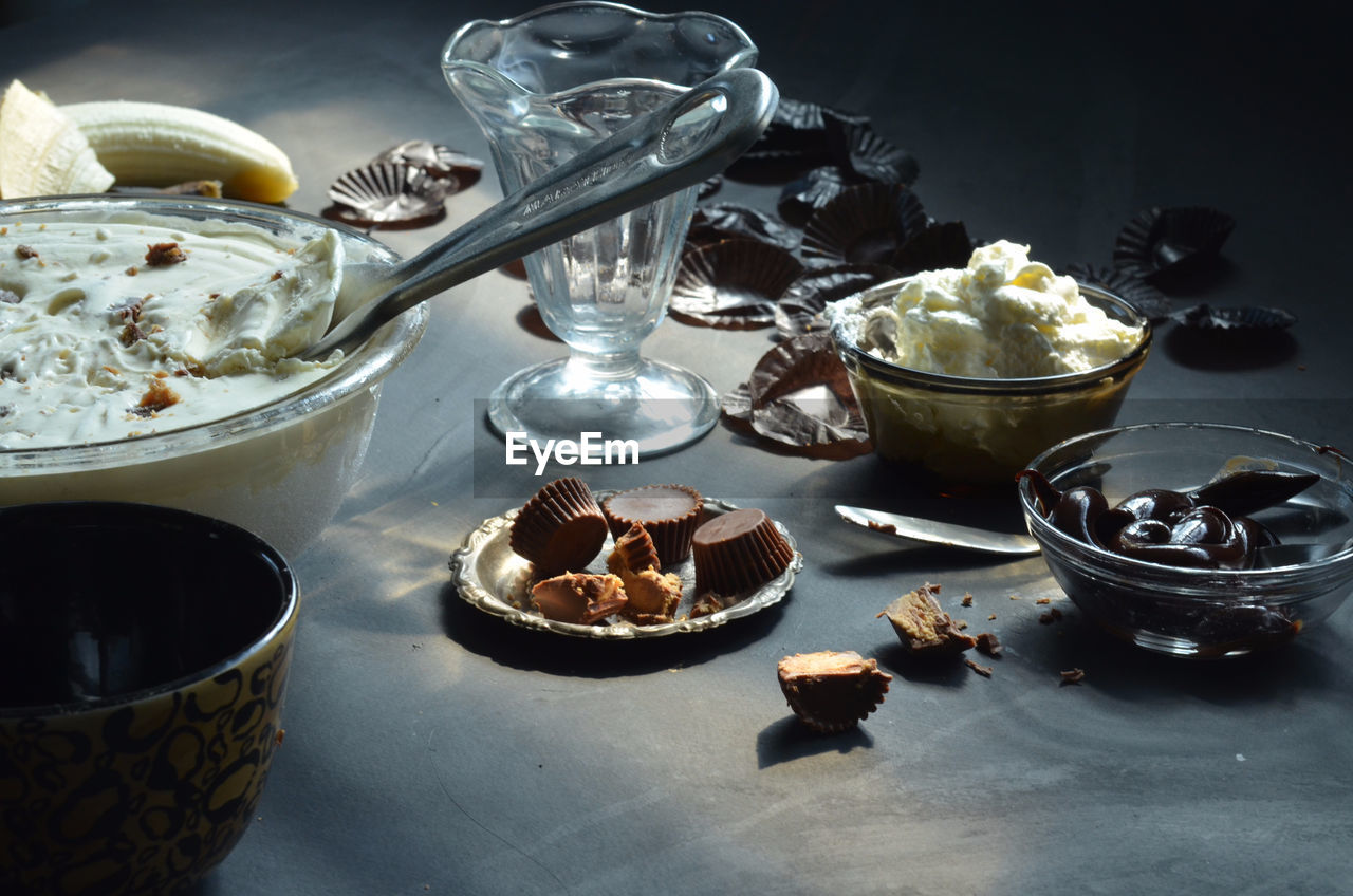 High angle view of ice cream in bowls with peanut butter cupcakes and chocolates on table