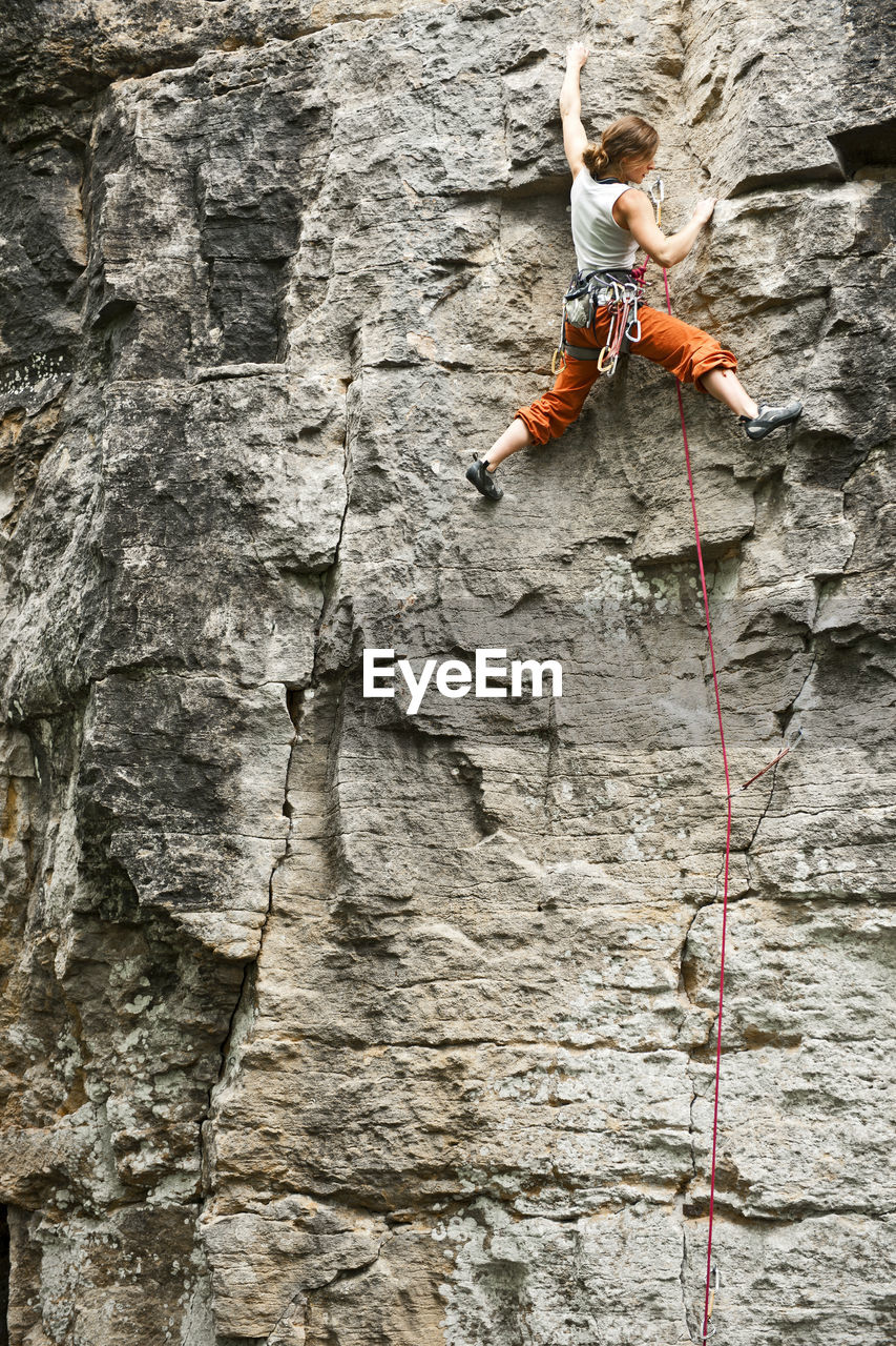 Young woman climbing rock face in france