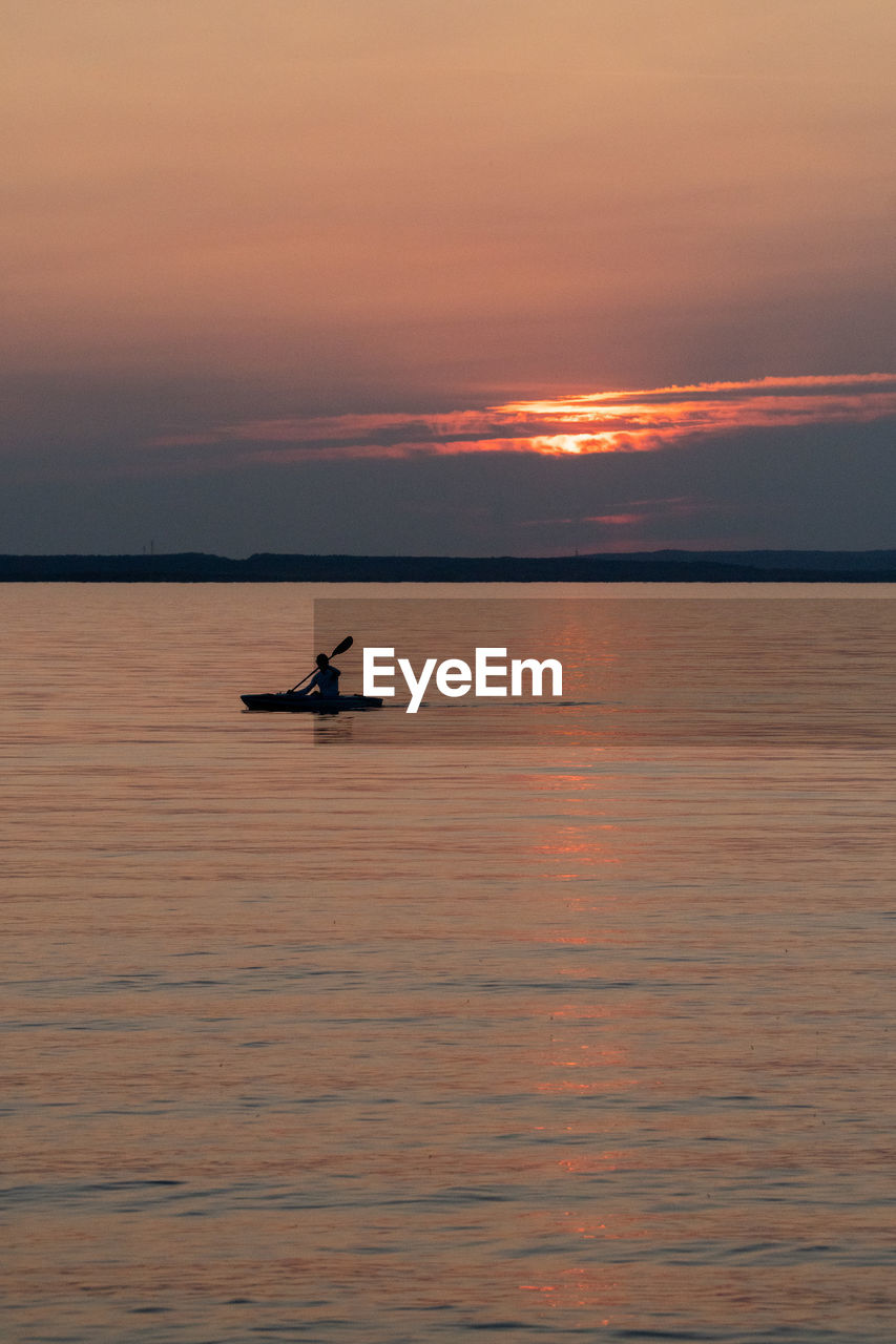 Silhouette boat in sea against orange sky