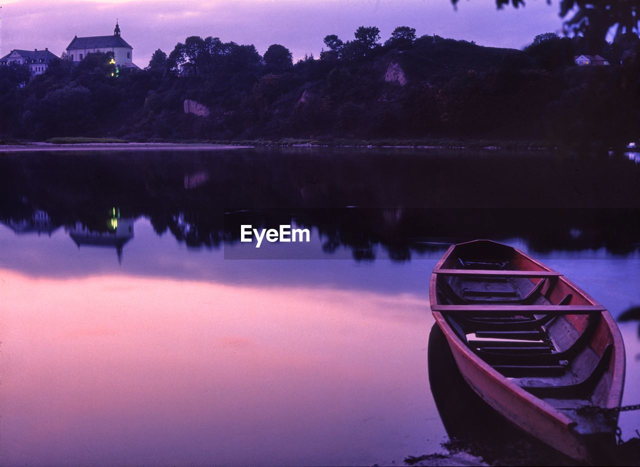 Boat moored on calm lake during sunset