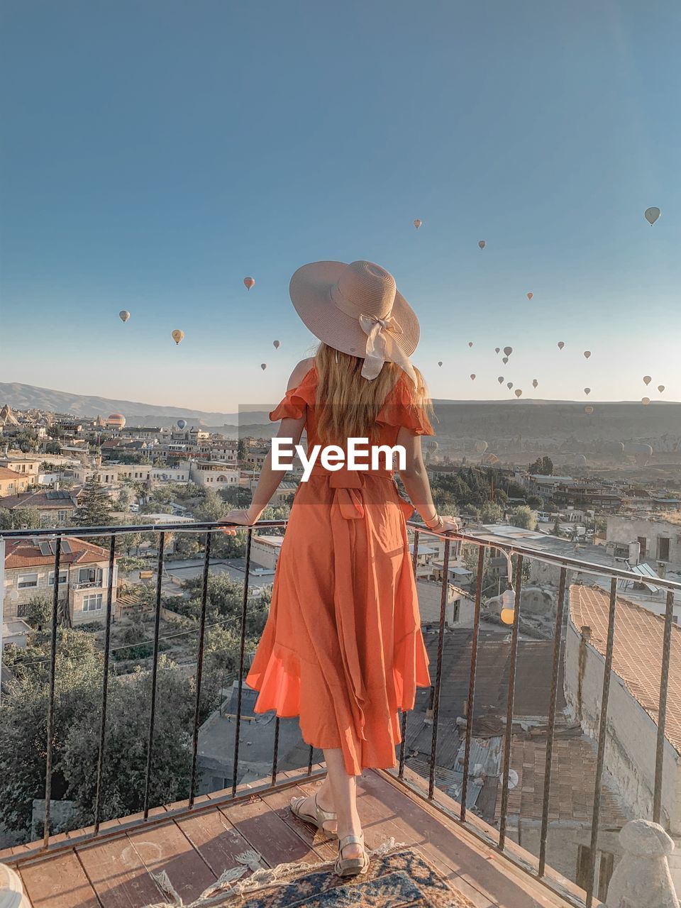 Rear view of woman looking at cityscape against sky