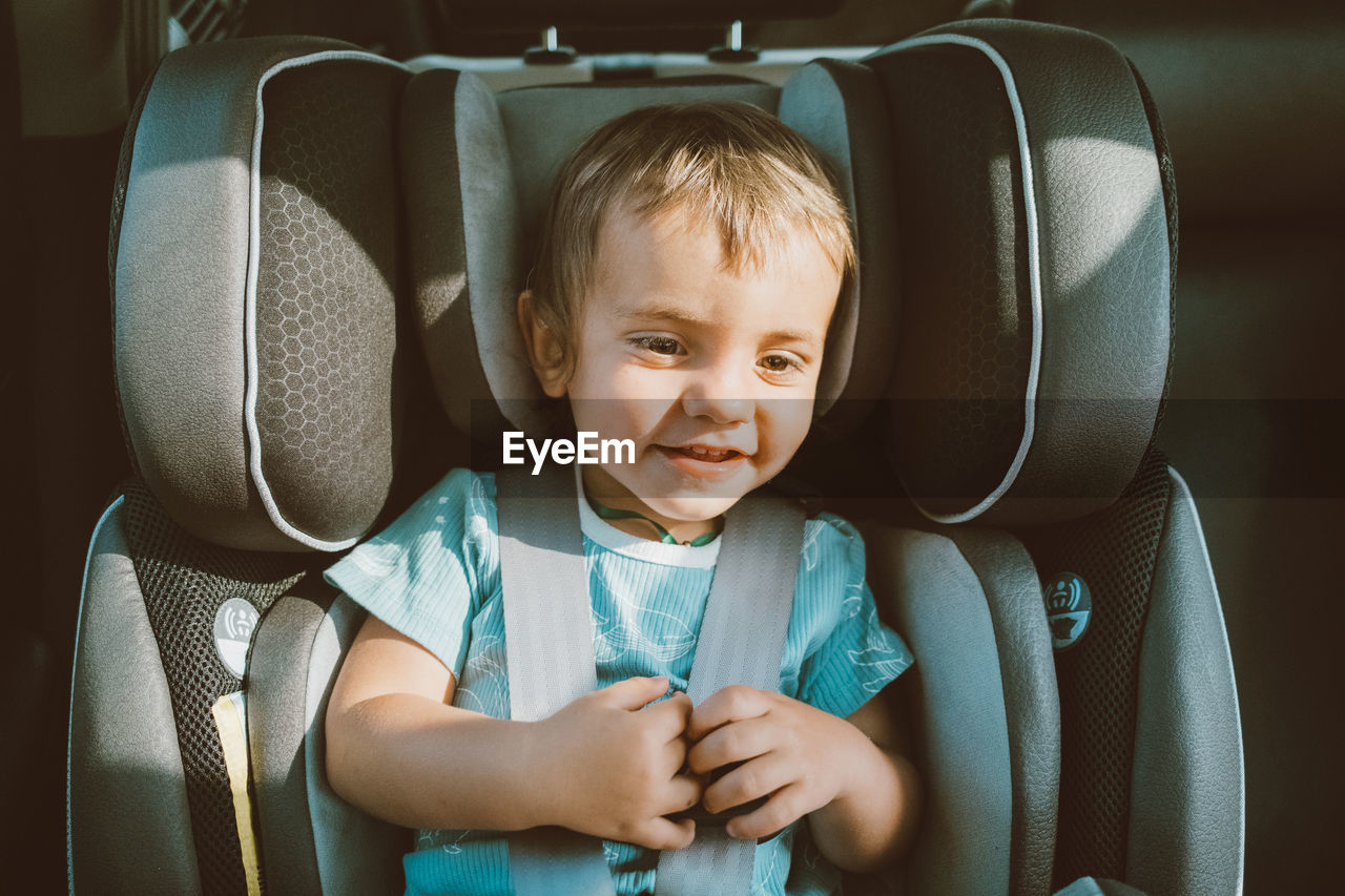 Cute baby boy sitting in car safety seat