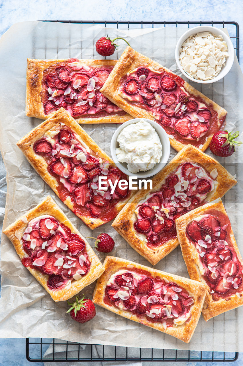 Strawberry, cream cheese and almond puff pastry pies on baking paper. 