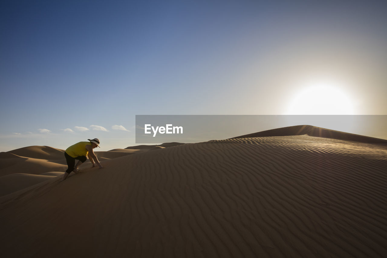 MAN RIDING HORSE ON SAND DUNES