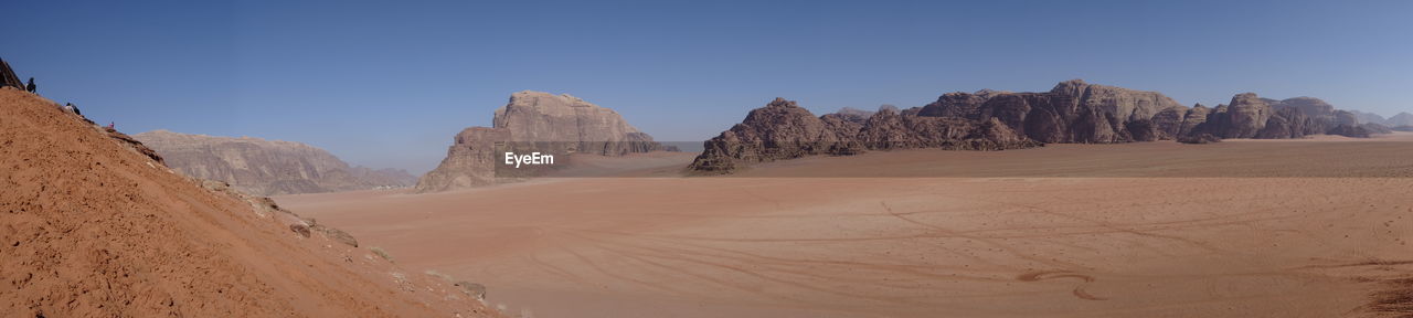 Panoramic view of desert against clear blue sky