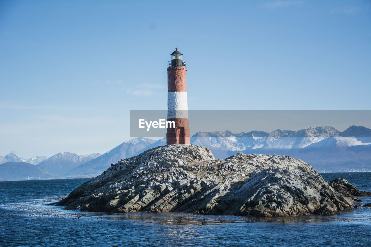 Lighthouse by sea against sky