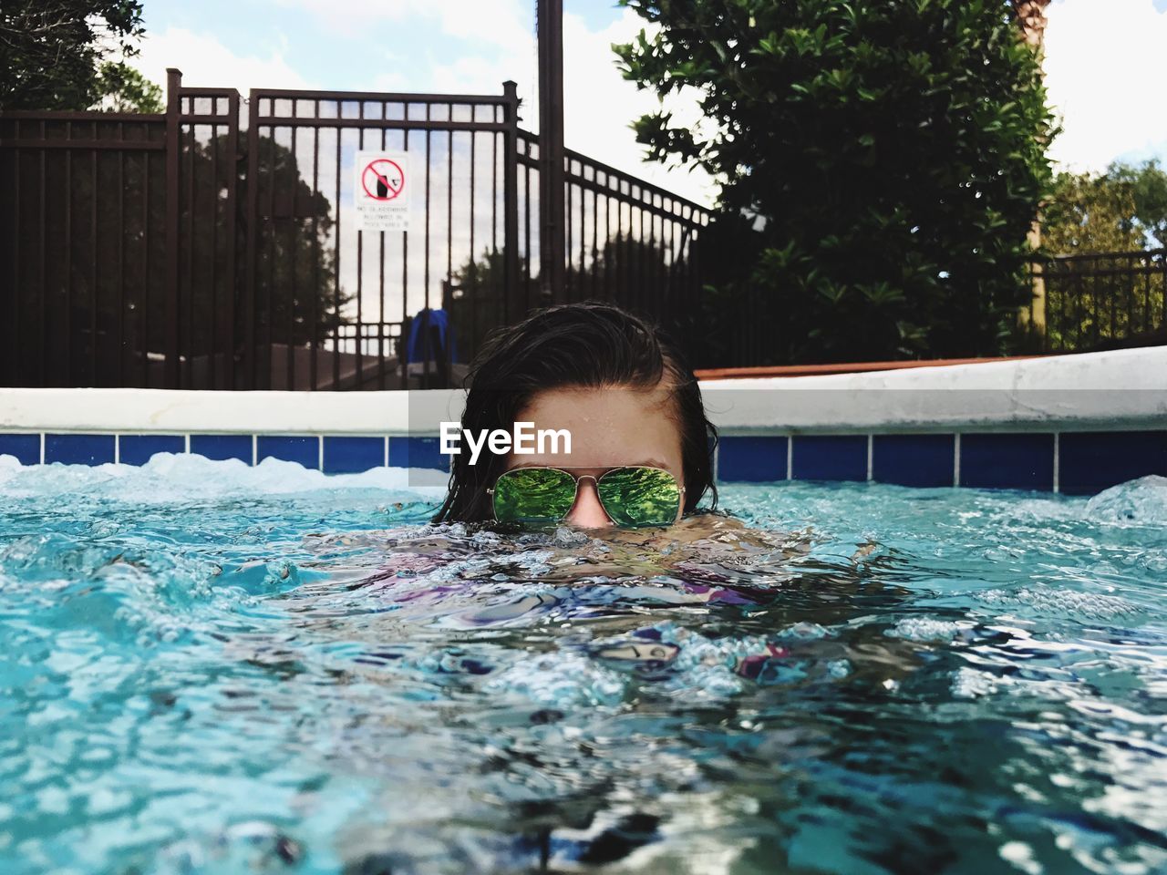 PORTRAIT OF WOMAN SWIMMING IN POOL AGAINST TREES