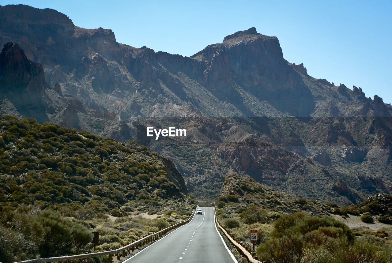 Road amidst mountains against clear sky