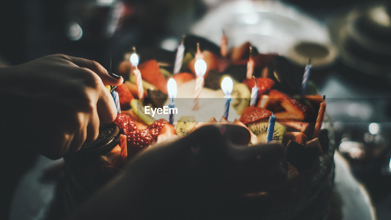 Close-up of woman igniting candles on birthday cake